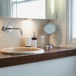 A bathroom vanity is lit by task lighting to light up the sink area.